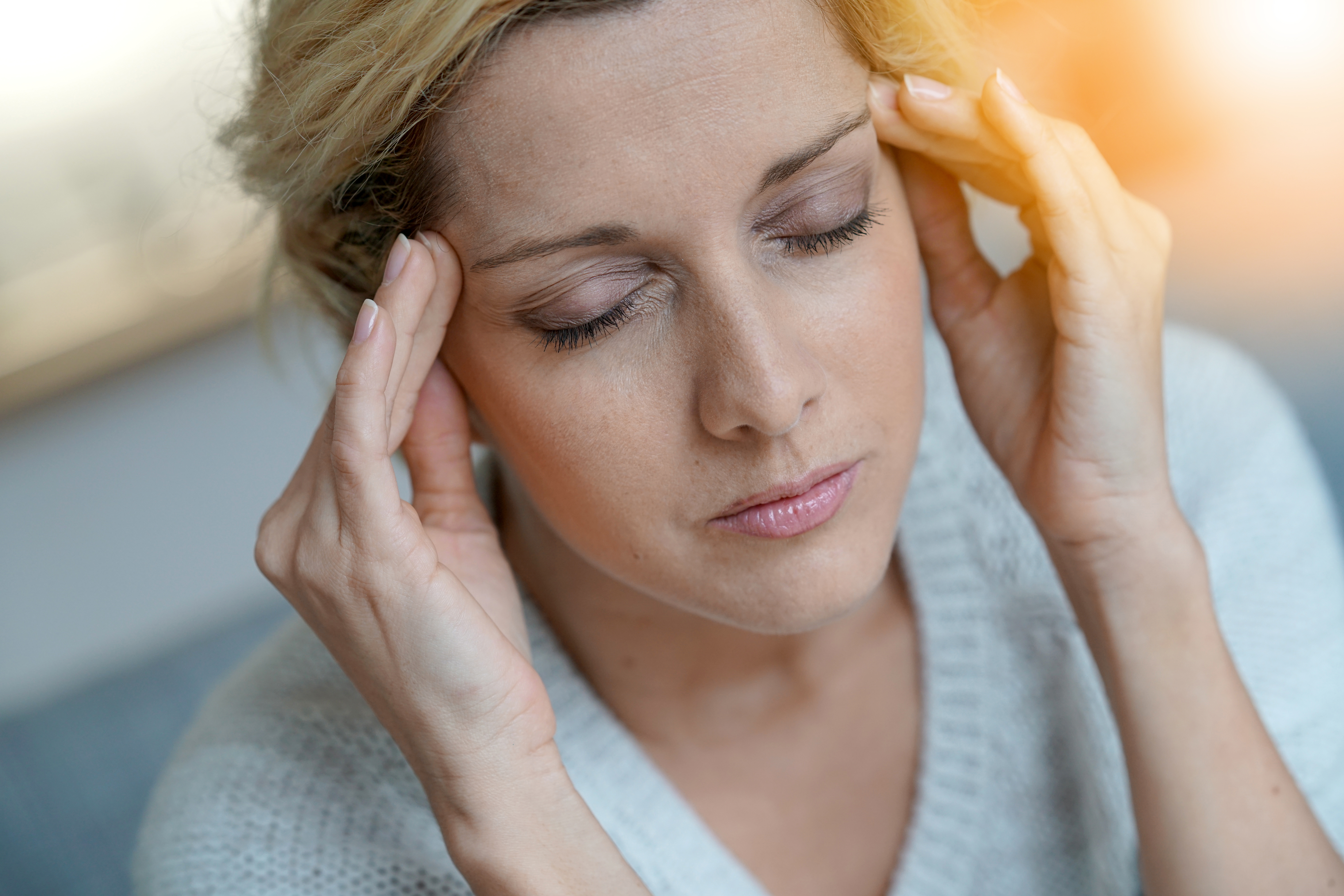 Portrait of middle-aged blond woman having a migraine