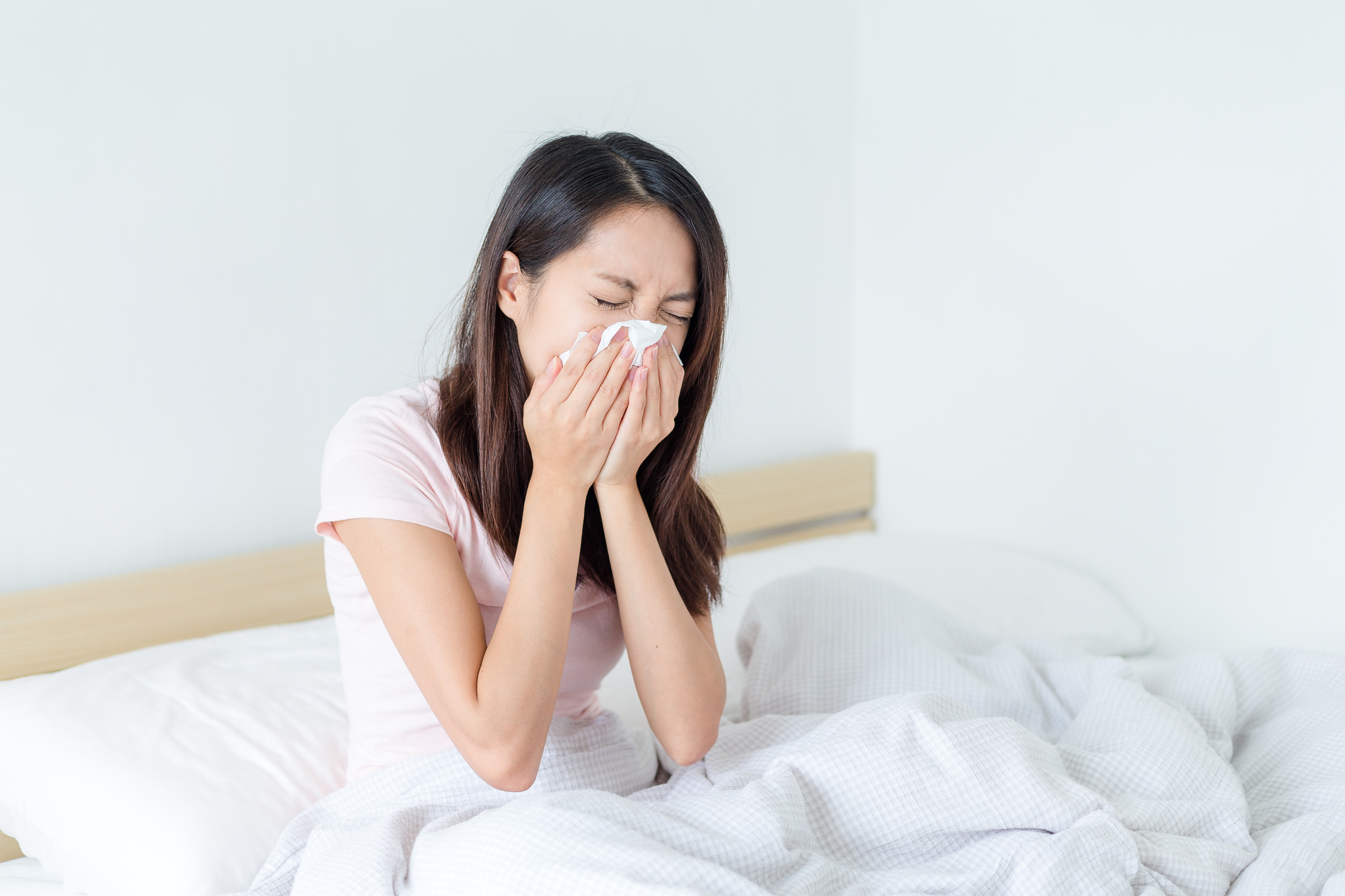 Woman sneezes in bed