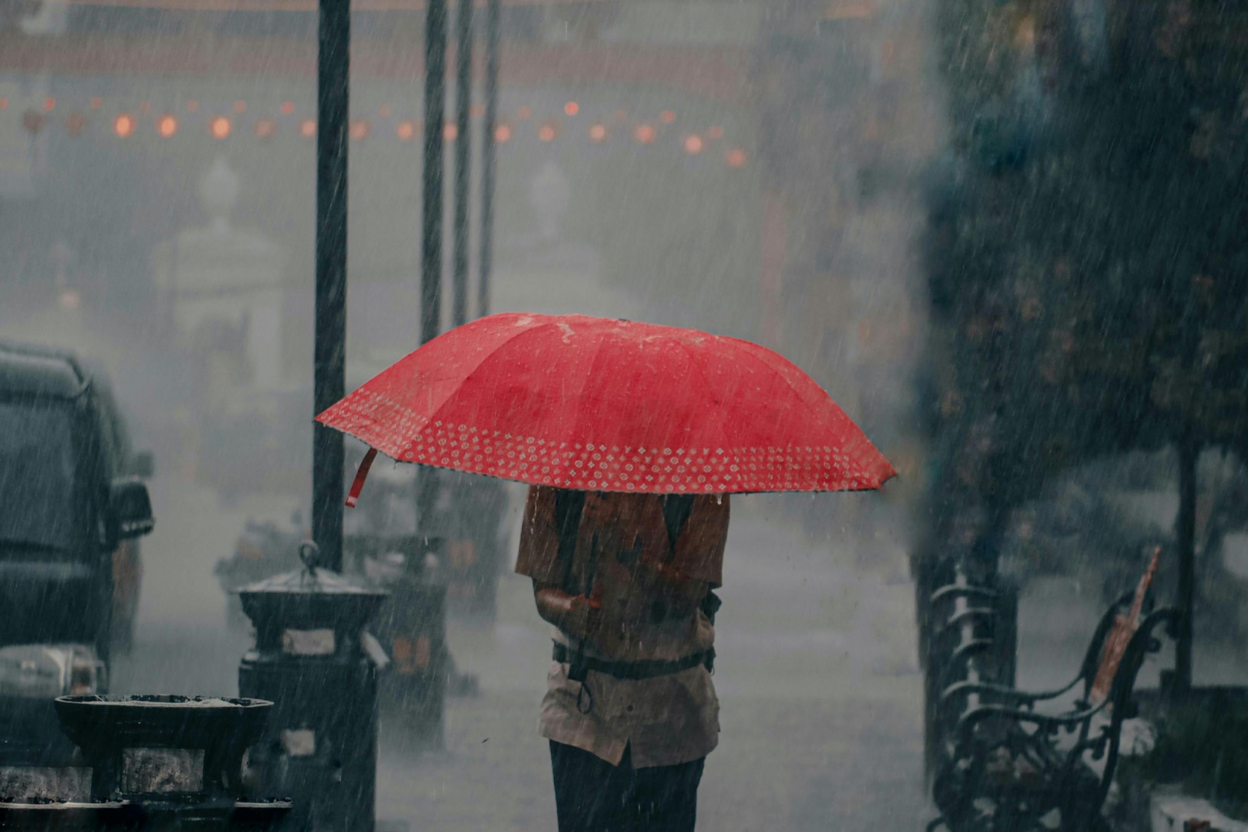 a man with a red umbrella in a rainstorm